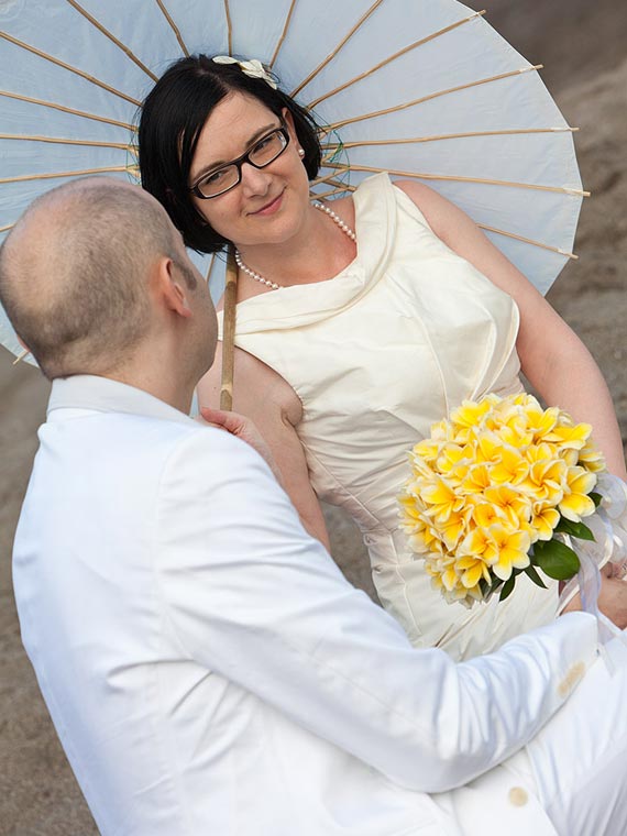 Hochzeitspaar mit Sonnenschirm am Strand Bali